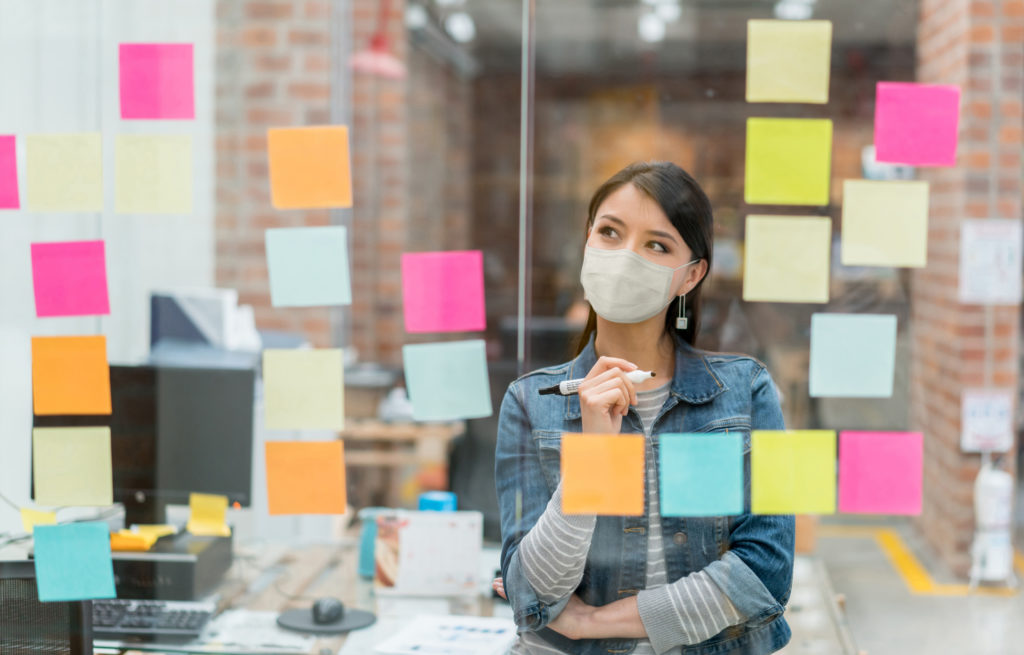 Caucasian Woman manager making decisions using a multicolored sticker wall for How To Pivot Your Digital Marketing After COVID: five Ways To Win blog post for apex cmo search