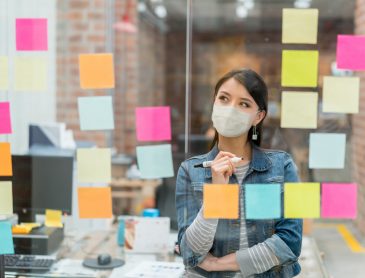 Caucasian Woman manager making decisions using a multicolored sticker wall for How To Pivot Your Digital Marketing After COVID: five Ways To Win blog post for apex cmo search